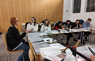 Mehrere Personen sitzen an Tischen für den Workshop: Kalligrafie