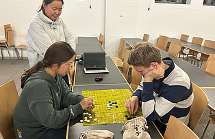 Drei Personen spielen das Go Spiel